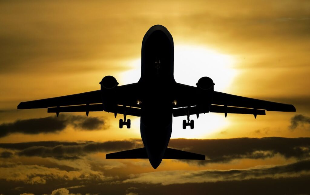Silhouette of an airplane flying against a dramatic sunset sky.